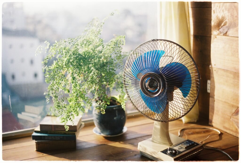 Ventilador de mesa ligado perto da janela em um dia de sol